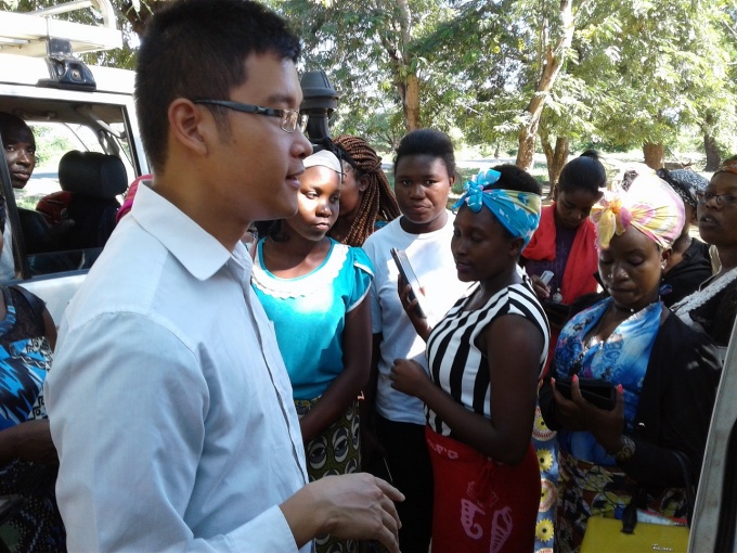 A male student standing among a group of health care workers in Malawi. 