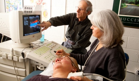 Ultrasound being performed by doctor and nurse on carotid artery of a patient. 